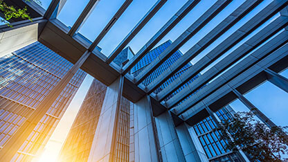 Bottom view of modern skyscrapers in business district against blue sky.  Building Exterior, Building - Activity, Construction Industry, Looking Up, Directly Below