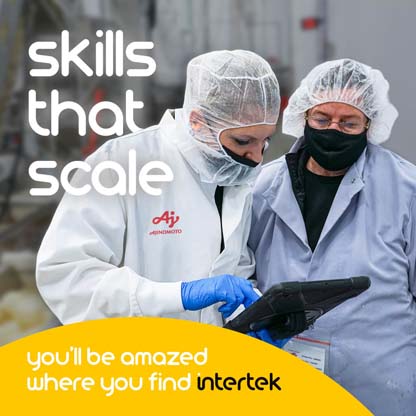 Two lab personnel wearing protective clothing consulting a large tablet