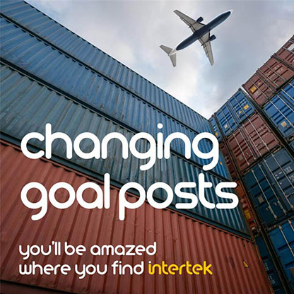 A plane overhead viewed through stacked cargo containers